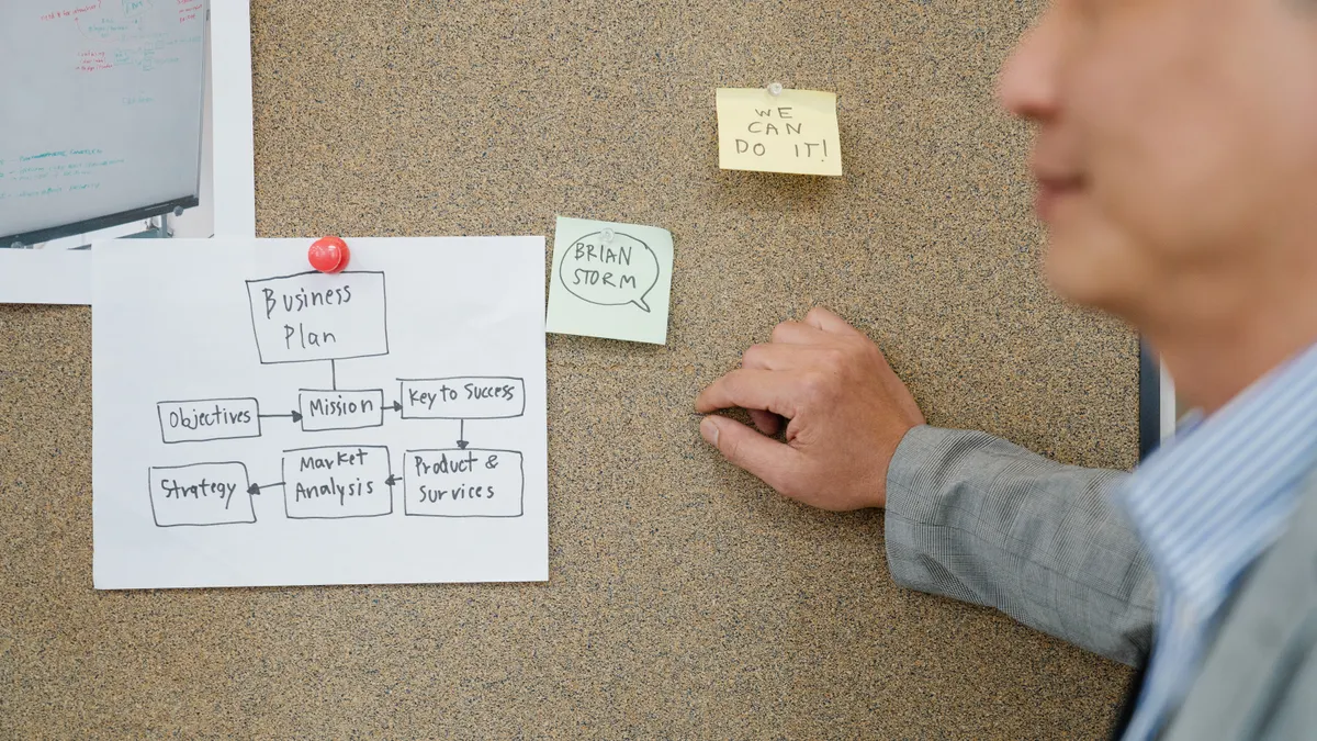 Person arranging a process diagram on a corkboard